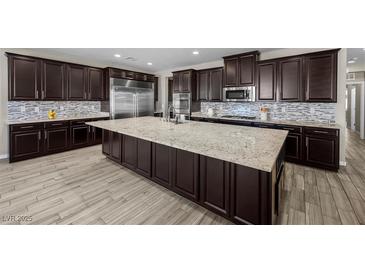 A spacious kitchen features a large center island, stainless steel appliances, and dark cabinetry at 3428 Royal Calloway Ave, Las Vegas, NV 89141