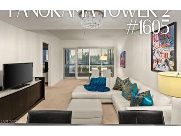 Bright living room featuring a white sofa, vibrant pillows, and a stunning city view from the large glass doors at 4575 Dean Martin Dr # 1605, Las Vegas, NV 89103