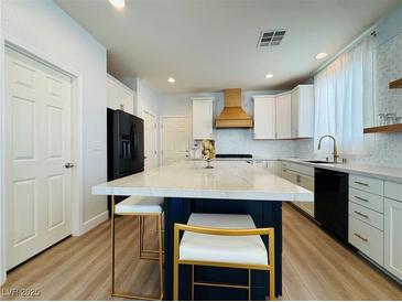 Modern kitchen features a large island with marble countertop, stainless steel appliances, and white cabinets at 6495 Little Harbor Ct, Las Vegas, NV 89141