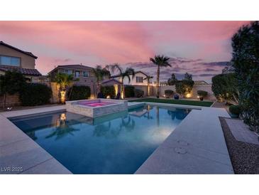 Beautiful backyard pool and spa surrounded by lush landscaping, perfect for relaxing and entertaining at sunset at 640 Hayborn Meadows St, Las Vegas, NV 89138