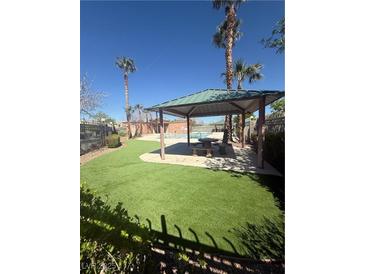 Relaxing pool area with shaded pergola, manicured lawn, and palm trees at 6546 Churnet Valley Ave, Las Vegas, NV 89139