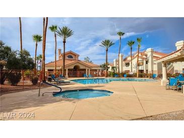 Community pool and hot tub with ample seating surrounded by palm trees at 725 Wheat Ridge Ln # 201, Las Vegas, NV 89145
