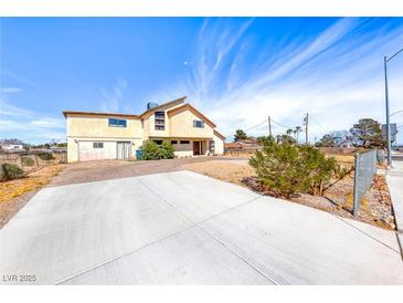 Two-story home with a long concrete driveway, desert landscaping, and a blue sky background at 9010 W Lone Mountain Rd, Las Vegas, NV 89129