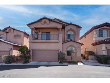 Two-story home with a balcony, arched windows, and a two-car garage, situated between other similar houses at 8307 Amtrak Express, Las Vegas, NV 89131