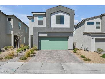 Contemporary two-story home featuring a gray facade, green garage door, and well-maintained landscaping at 10214 Natural Anchor St, Las Vegas, NV 89166