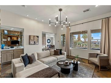 Bright living room featuring a large sectional sofa, modern chandelier, and an open view of the outdoor landscape at 2822 Soft Horizon Way, Las Vegas, NV 89135