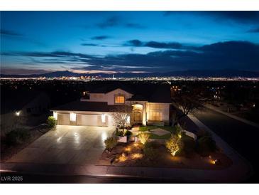 Striking home exterior at night showcasing a three-car garage and professionally landscaped front yard with landscape lighting at 979 Evening Dew Dr, Las Vegas, NV 89110