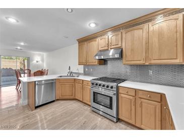 Bright kitchen features stainless steel appliances, light wood cabinetry, and elegant countertops, seamlessly connecting to dining area at 10955 Sospel Pl, Las Vegas, NV 89141