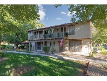Two-story townhome with a balcony, green lawn, and mature shade trees on a sunny day at 3189 Pinehurst Dr # B, Las Vegas, NV 89109