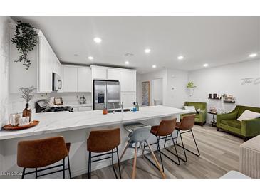 Modern kitchen featuring white cabinets, stainless steel appliances, and a large marble countertop island with seating at 6144 Rathbone St, Las Vegas, NV 89166