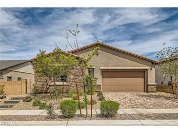 Charming single-story home showcasing a stone facade, a two-car garage, and a meticulously landscaped front yard at 728 Omaggio Pl, Henderson, NV 89011