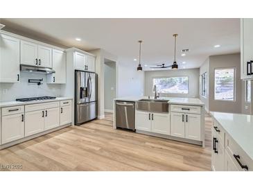 Bright kitchen showcasing white cabinets, stainless steel appliances, and a large island with sink and quartz countertop at 3017 Walnut Park Ct, Henderson, NV 89052