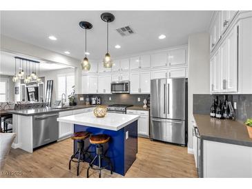 Bright kitchen boasts white cabinets, a blue island, and stainless steel appliances at 69 Via Di Mello, Henderson, NV 89011