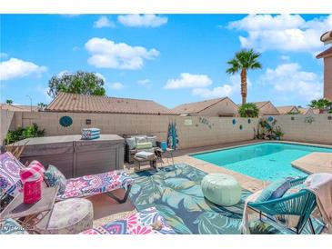 Inviting backyard featuring a sparkling pool, spa, and cozy outdoor seating area for relaxation and entertaining at 7845 Scammons Bay Ct, Las Vegas, NV 89129