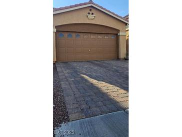 A two car garage with a brick driveway offers parking and curb appeal at 8117 Discovery Point St, Las Vegas, NV 89139