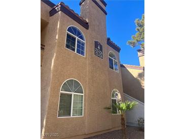 Exterior shot of a sand-colored condo building with arched windows and terra cotta roofing under a blue sky at 9325 W Desert Inn Rd # 174, Las Vegas, NV 89117