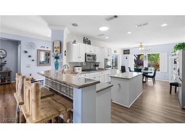 Bright kitchen featuring white cabinets, granite countertops, stainless steel appliances, and an island with breakfast bar at 2606 Crested Butte St, Henderson, NV 89052
