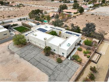 An aerial view of a home with solar panels, a three-car garage, and landscaping, set against a desert backdrop at 3910 W Pebble Rd, Las Vegas, NV 89139