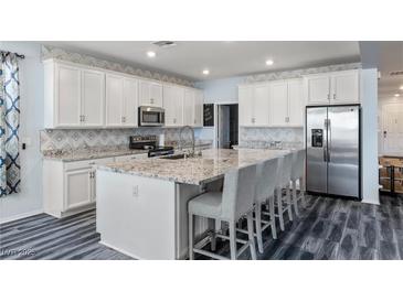 Bright kitchen features white cabinetry, stainless appliances, and granite countertops with an island and barstool seating at 4801 Westmont Dr, Pahrump, NV 89061