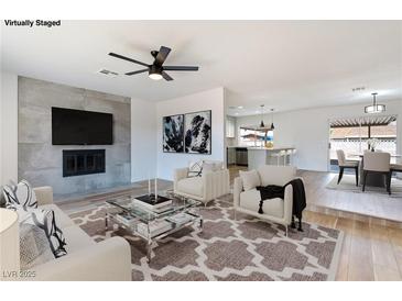 Cozy living room features a fireplace, ceiling fan, and a view to the kitchen and dining area at 5804 Maynard Ave, Las Vegas, NV 89108