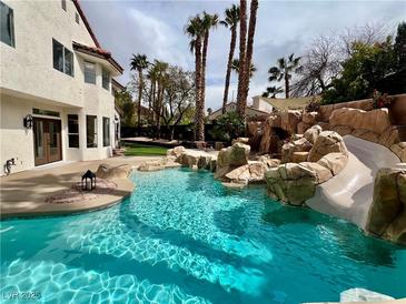 Backyard pool features rock waterfall, water slide, and lush landscaping at 8913 Saint Pierre Dr, Las Vegas, NV 89134