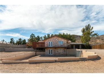 Two-story home with stone accents, a second story balcony, and desert landscaping at 9865 Penny Ln, Las Vegas, NV 89178