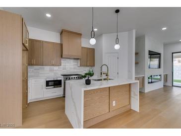 Modern kitchen featuring stainless steel appliances, wood cabinetry, and a marble island with pendant lighting at 10452 Niagara Falls Ln, Las Vegas, NV 89144