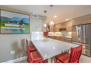 Bright kitchen features a breakfast bar with white countertops, red bar stools, and stainless steel appliances at 205 E Harmon Ave # 1007, Las Vegas, NV 89169