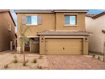 Two-story home with a tan exterior, brown shutters, two-car garage and desert landscaping at 4253 Gold Desert St, North Las Vegas, NV 89032