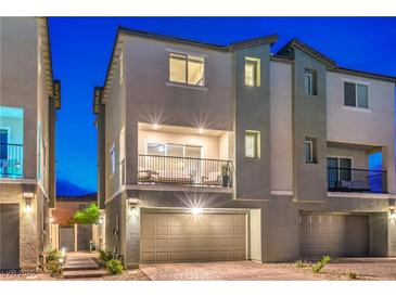Modern two-story townhome featuring a private balcony and a two-car garage at twilight at 6821 Prairie Pearl St, Las Vegas, NV 89148