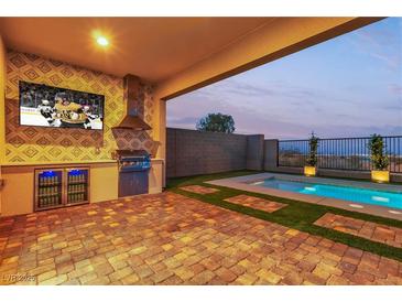 Covered outdoor kitchen, TV, and barbecue area near pool with desert view at 154 Nine Mile Creek Dr, Las Vegas, NV 89138