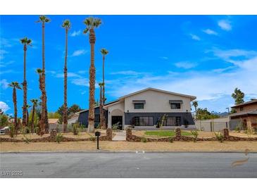 Charming two-story home boasting desert landscaping, a dark blue accent wall, and tall palm trees at 2685 S Tenaya Way, Las Vegas, NV 89117