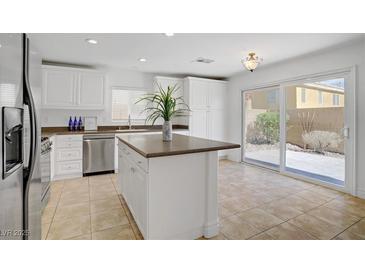 Bright kitchen features an island, stainless steel appliances, white cabinets, and sliding glass doors to the backyard at 236 Dog Leg Dr, Las Vegas, NV 89148