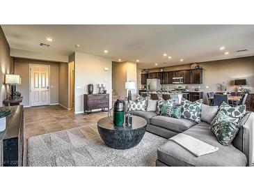 Open-concept living room boasts modern decor, including a large sectional sofa and adjacent gourmet kitchen at 2674 Duneville St, Las Vegas, NV 89146