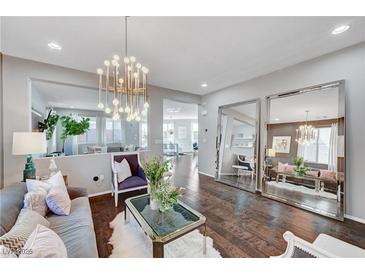 Bright living room features a modern chandelier, hardwood floors, and large decorative mirrors at 5662 Escamilla Rd, Las Vegas, NV 89135