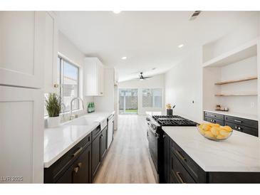 Bright open kitchen boasts white cabinets, dark island, and stainless steel appliances at 5828 Red Gull St, Las Vegas, NV 89149