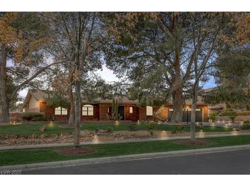 Charming single-story brick home with a lush green lawn and mature shade trees at 9 Quail Run Rd, Henderson, NV 89014