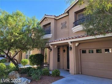 Tan two-story home featuring a two car garage, balcony, desert landscaping and covered front porch entry at 9758 Panther Hollow St, Las Vegas, NV 89141