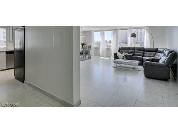 Bright living room featuring tile flooring, a modern gray sofa, and an open floor plan with large bright windows at 205 E Harmon Ave # 511, Las Vegas, NV 89169