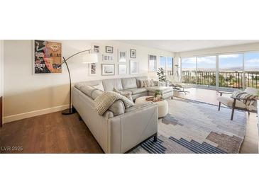 Open-concept living room featuring a gray sectional sofa, stylish decor, and sliding doors leading to a balcony with a view at 3111 Bel Air Dr # 10F, Las Vegas, NV 89109