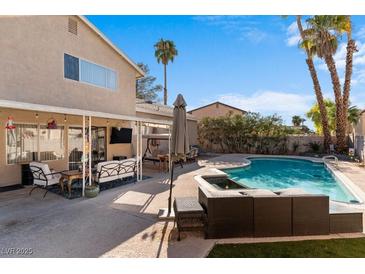 Inviting backyard features a sparkling pool, spa, and covered patio with comfortable seating under a blue sky at 1708 Crest Ave, Las Vegas, NV 89119