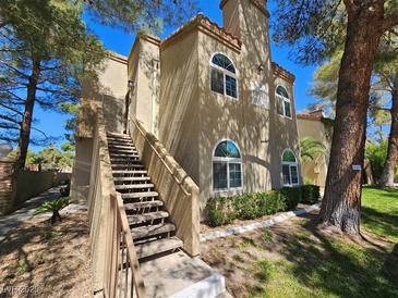 Two story condo featuring stairs leading up to entrance and well manicured lawn with mature trees at 3145 E Flamingo Rd # 2005, Las Vegas, NV 89121