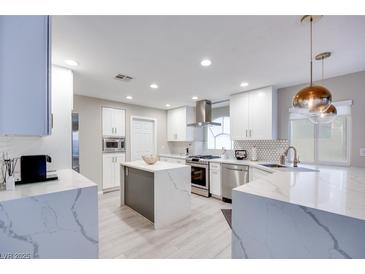 Bright, modern kitchen features white cabinetry, stainless steel appliances, and a large island at 4211 Saxton Green Ave, Las Vegas, NV 89141