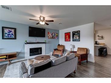 Inviting living room featuring a cozy fireplace and ceiling fan at 117 Saint Albans Ct, Henderson, NV 89015