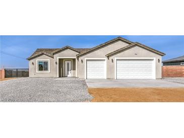 Charming single-story home featuring a two-car garage, gravel landscaping, and stucco siding at 3120 S Torrey Pines Ave, Pahrump, NV 89048