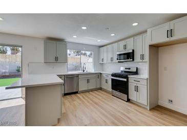 Modern kitchen features stainless steel appliances, light grey cabinetry and a breakfast bar that opens to backyard access at 4855 San Sebastian Ave, Las Vegas, NV 89121