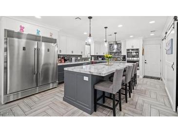 Bright, open kitchen featuring a large island with marble countertop, pendant lighting, and stainless steel appliances at 6995 Rogers St, Las Vegas, NV 89118