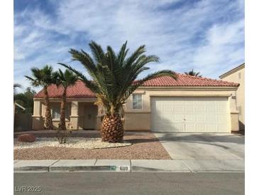 Charming single-story home featuring a well-manicured front yard with mature palm trees and a two-car garage at 6119 Magic Mesa St, North Las Vegas, NV 89031