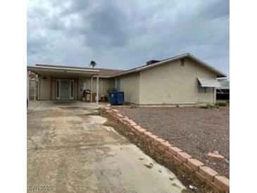 Modest single story home featuring tan siding, carport, and low brick wall at 6733 E Carey Ave, Las Vegas, NV 89156
