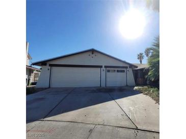 Exterior front view of a home with a two-car garage and wide driveway on a sunny day at 1673 Caliente Ct, Las Vegas, NV 89119